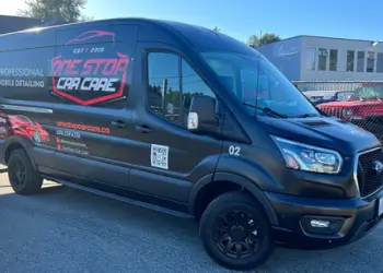 Black One Stop Car Care mobile service van with red and white branding, website info, QR code, and a red sports car graphic, parked in a commercial area.