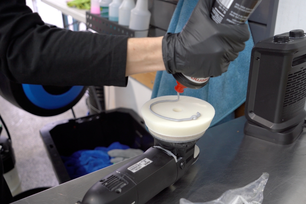 A detailer in Surrey, BC applies polishing compound to a foam pad on a dual-action polisher during the Surface Preparation & Paint Correction stage before ceramic coating application.