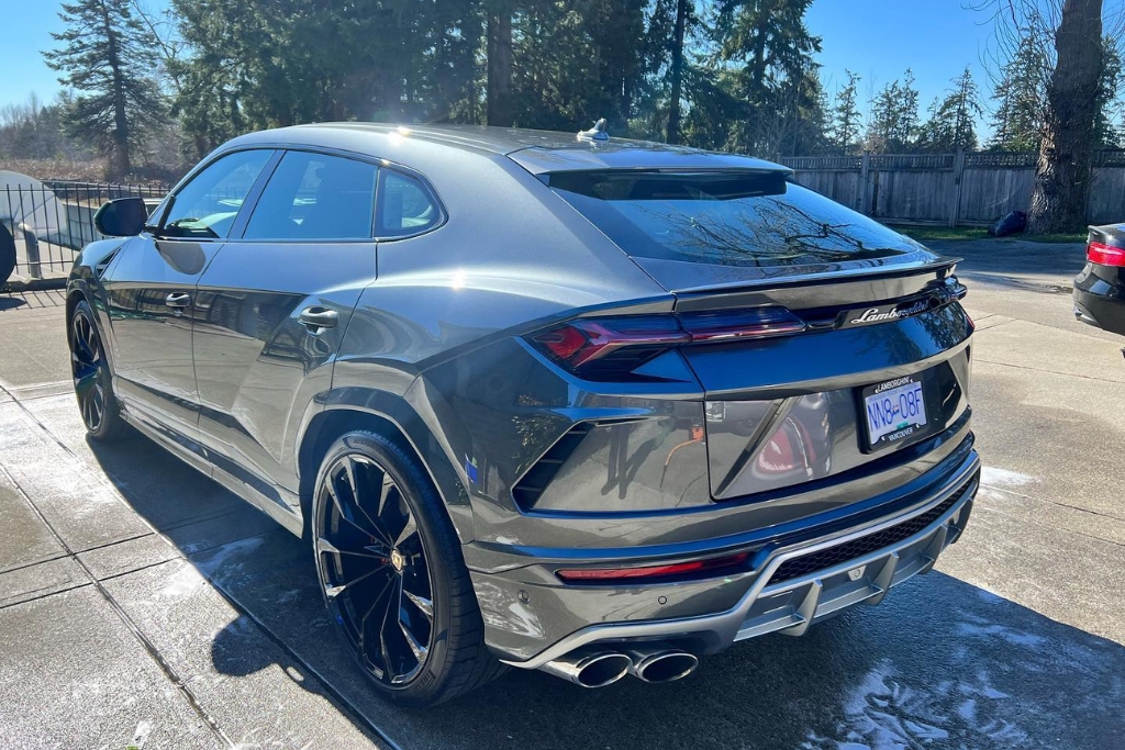 A shiny grey Lamborghini SUV parked outdoors in Surrey, reflecting sunlight off its flawless paint after a professional paint protection film application. The image shows how PPF preserves gloss and prevents UV-induced fading.