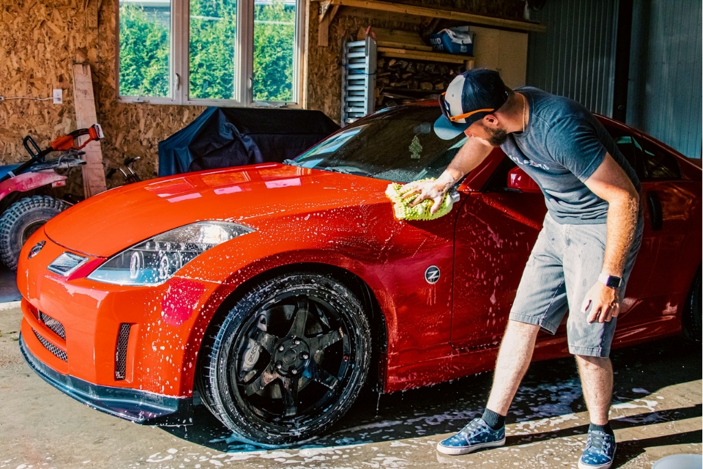 A man in Surrey, BC hand-washes a bright red sports car using a microfiber mitt and pH-neutral soap, demonstrating proper Maintenance Tips for preserving a ceramic-coated finish.