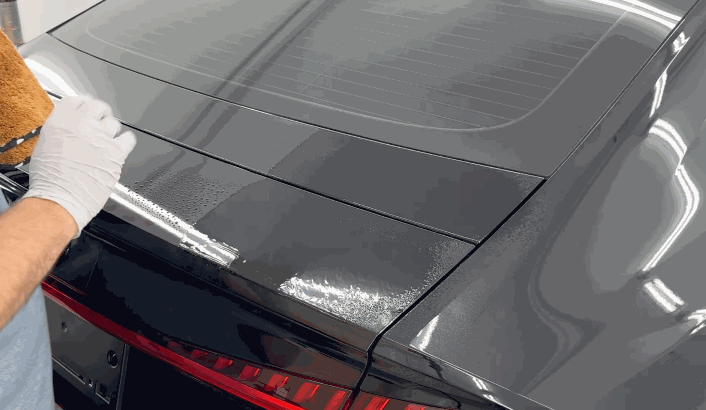 Person wiping a freshly coated car trunk with a microfiber cloth, enhancing gloss and chemical resistance.