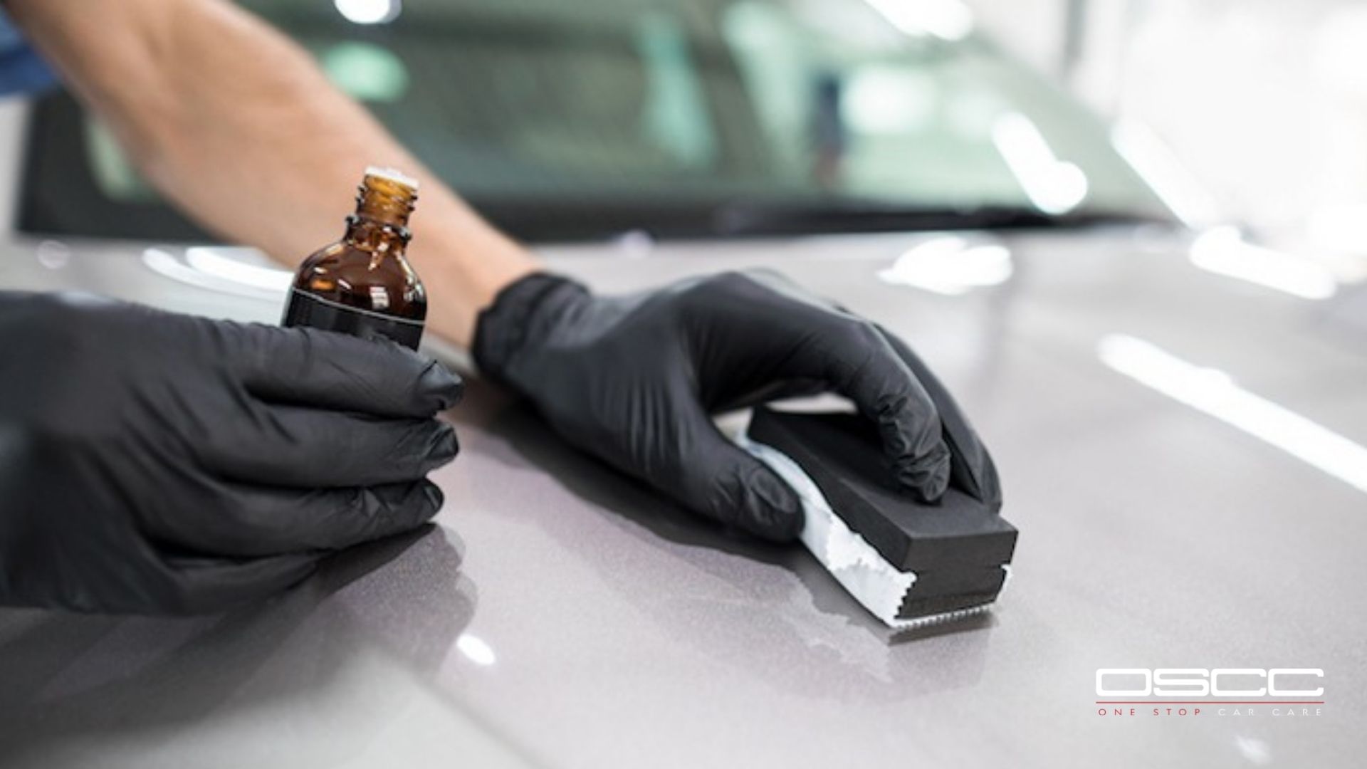 Close-up of ceramic coating application with a gloved hand using a foam block and microfiber suede cloth on a metallic hood.
