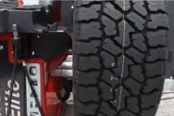 Close up of a rugged tire with deep tread mounted on a balancing machine in a professional auto shop. The image emphasizes precise tire balancing and installation services in Surrey to improve safety and extend tire life.