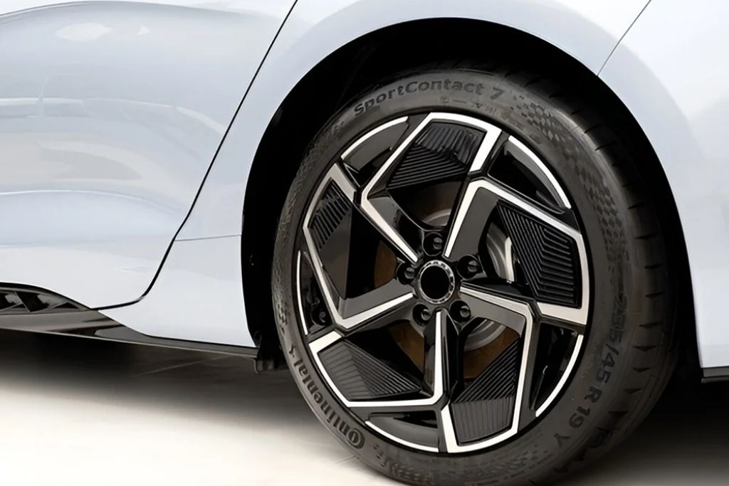 Large aftermarket alloy rim with low-profile tire installed on a white car, showcasing a modern custom wheel design