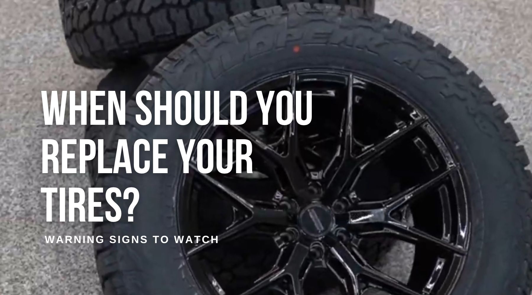 Close-up of a black off-road tire and custom black rim with blog text about when to replace your tires.