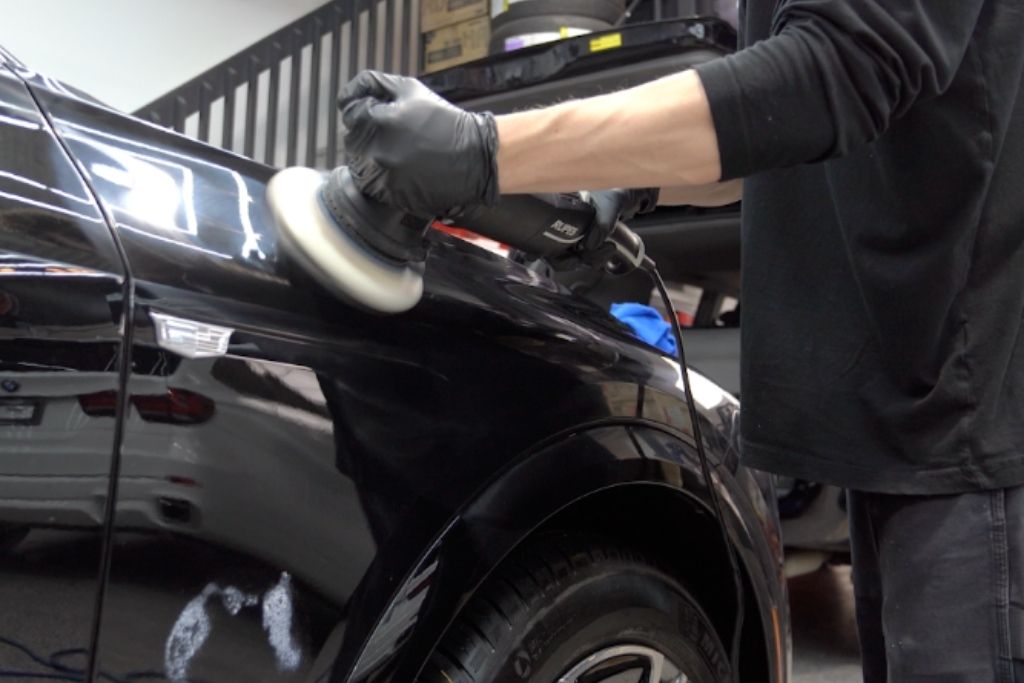 Technician polishing a black car during professional exterior detailing in Surrey, BC.