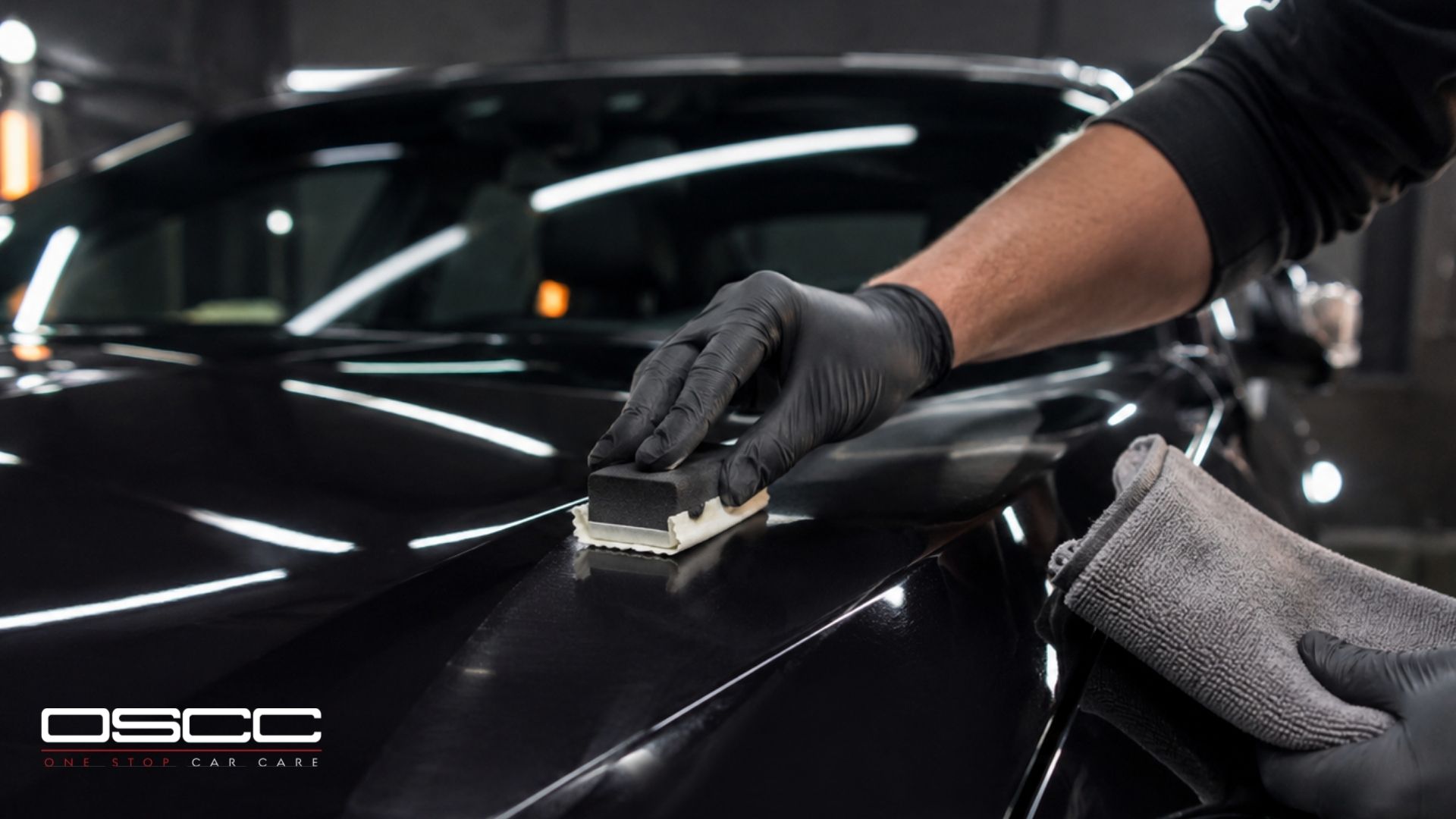 Technician applies ceramic coating to a black car hood with an applicator pad.